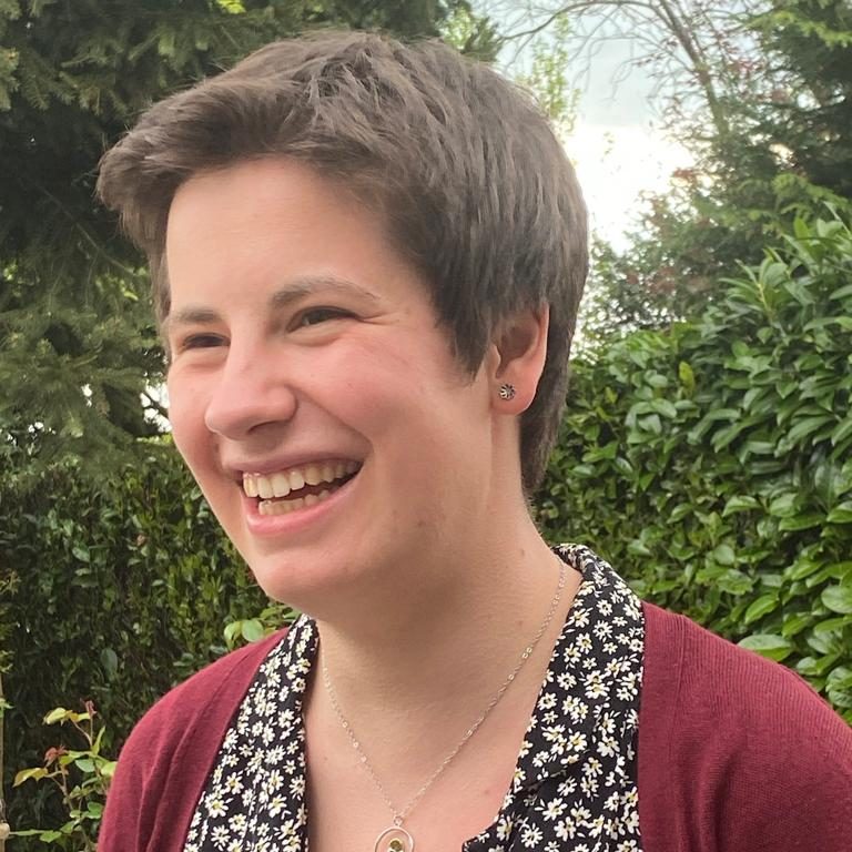 image of Beth Davies, smiling with short brown hair outside with trees